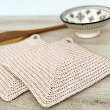 Lade das Bild in den Galerie-Viewer, Ein Paar beige gehäkelte Topflappen liegen auf einer hellen Holz-Platte mit Keramik-Schalen im Hintergrund
