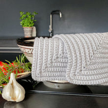 Lade das Bild in den Galerie-Viewer, Hellgraue gehäkelte Topflappen die in einer schwarz-weissen Schale liegen