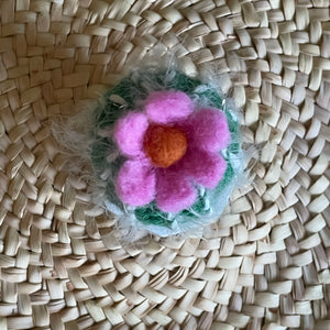 Kleiner gehäkelter Kaktus mit pinkfarbener Blüte in einem Keramiktopf von oben