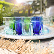 Load image into Gallery viewer, Grüne, blaue und transparente Gläser zu 100% aus recyceltem Glas auf einem Tablett im Sonnenschein 
