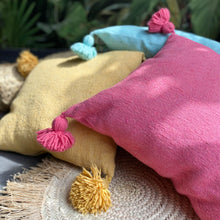 Load image into Gallery viewer, Pompom-Kissen aus Baumwolle in Pink, Türkis und Gelb im Sonnenlicht 
