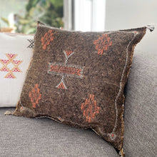 Load image into Gallery viewer, Wunderschönes, handgefertigtes Kissen in Schokobraun mit aufwendigen Stickereien auf einem Sofa
