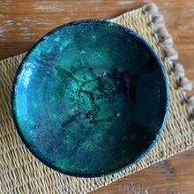 Load image into Gallery viewer, Eine marokkanische handgearbeitete grüne Keramik-Schale aus Tamegroute steht auf einem Seegras-Platzdeckchen mit Quasten
