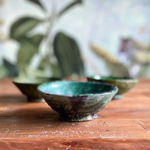Drei marokkanische handgearbeitete grüne Keramik-Schalen stehen auf einem Vintage-Holztisch 