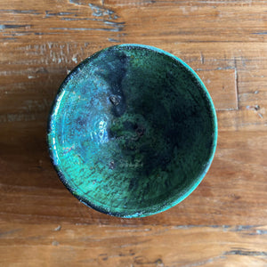 Eine marokkanische handgearbeitete grüne Keramik-Schale steht auf Vintage-Holztisch