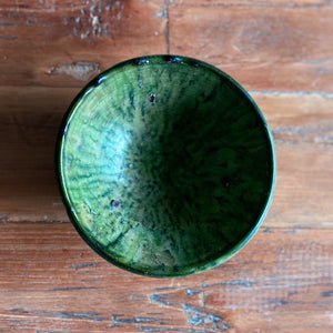 Eine marokkanische handgearbeitete grüne Keramik-Schale steht auf Vintage-Holztisc