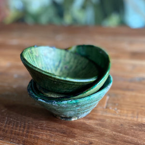 Ein Stapel aus marokkanischen handgearbeiteten grünen Keramik-Schalen, die auf einem Holztisch stehen