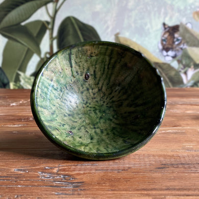 Eine marokkanische handgearbeitete grüne Keramik-Schale steht auf Vintage-Holztisc