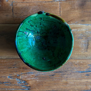 Eine marokkanische handgearbeitete grüne Keramik-Schale steht auf Vintage-Holztisch 