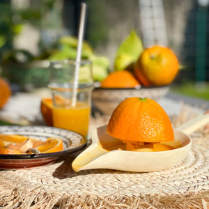 Zitruspresse mit Orangen und einem Glas frisch gepresstem Orangensaft auf Tisch im Ibizastyle